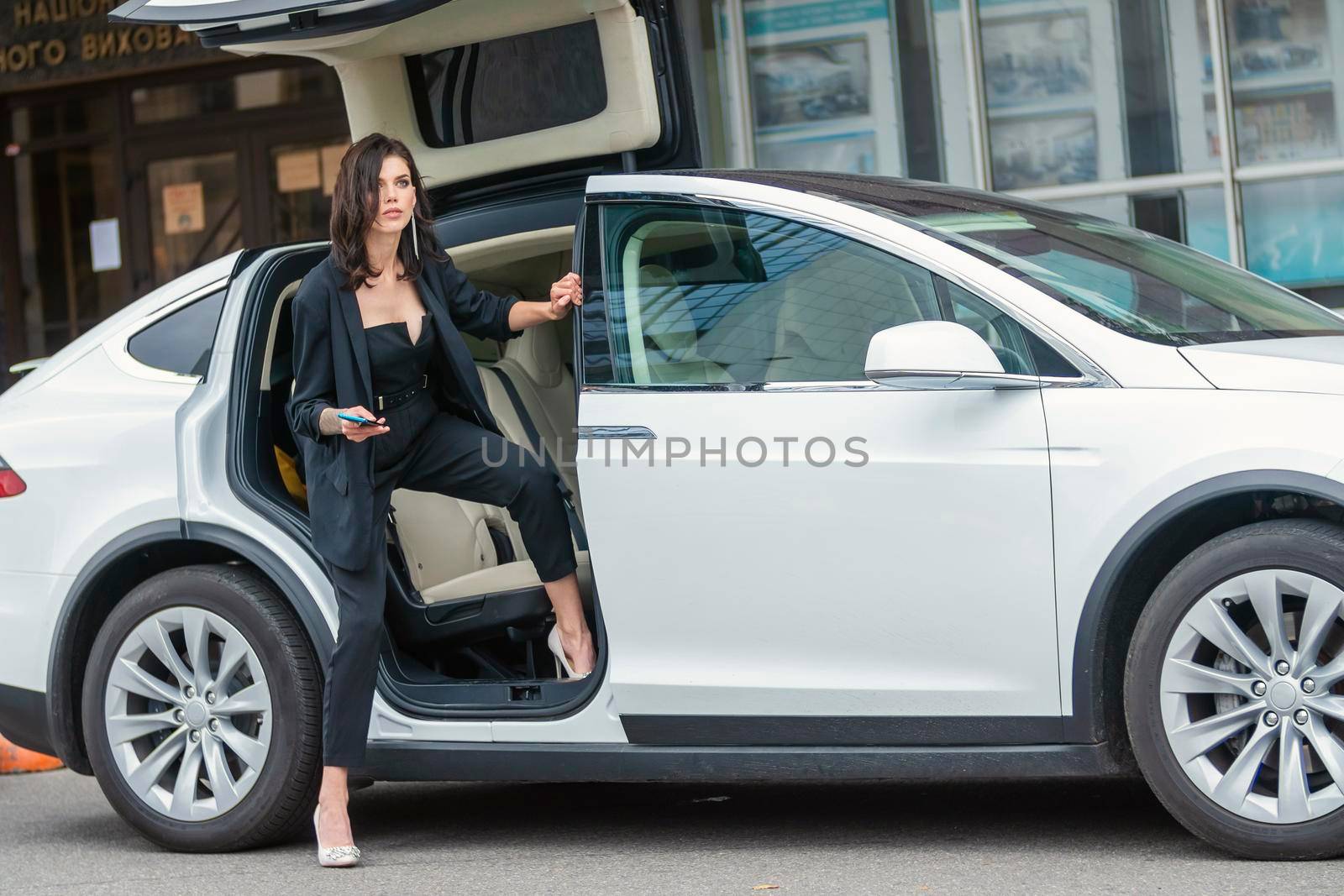 a woman in a business suit sits in a car by zokov
