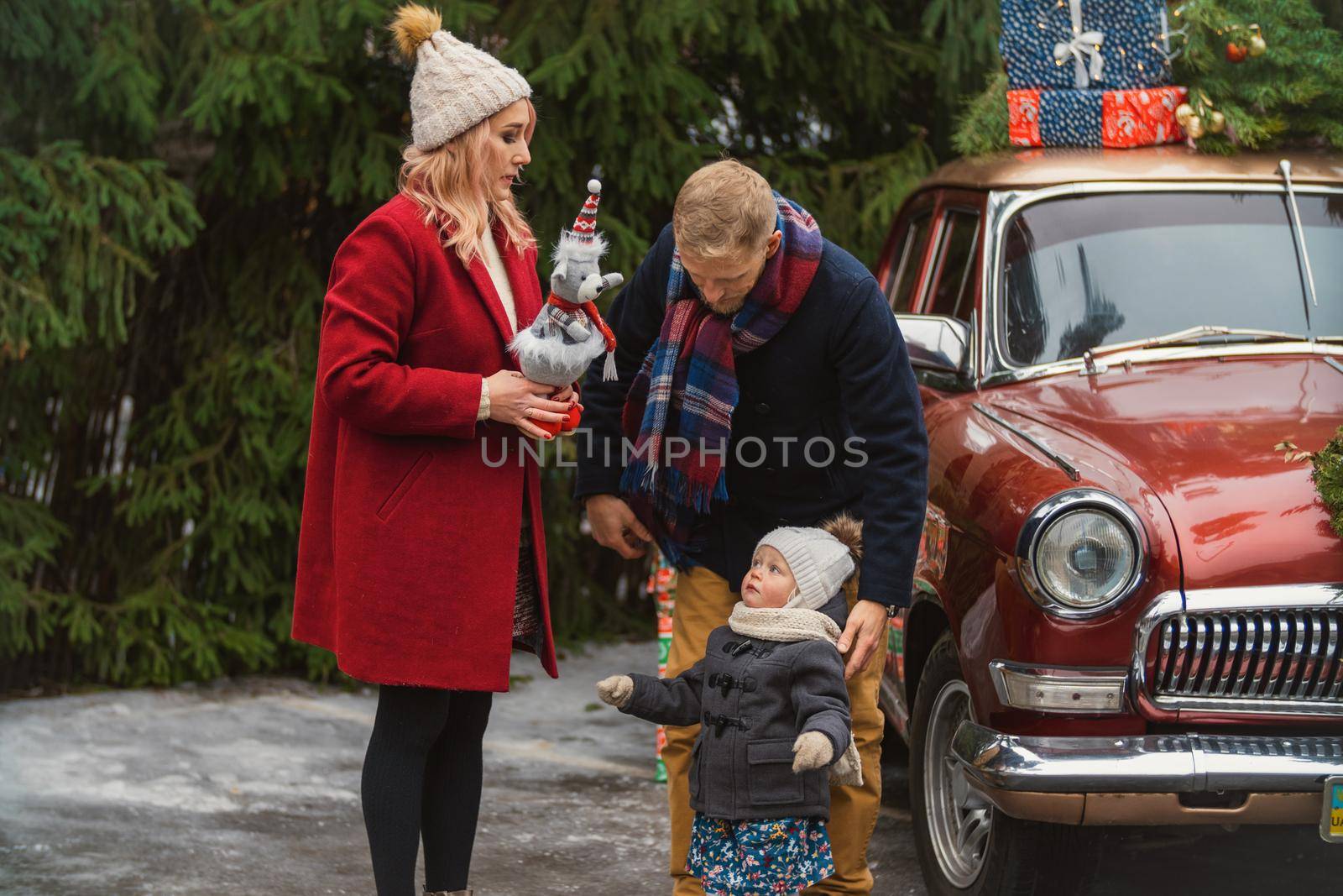 family near retro car with gifts in the parking lot near the park