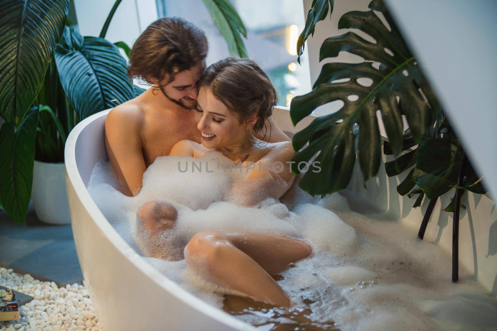 beautiful couple lies in a bath with foam