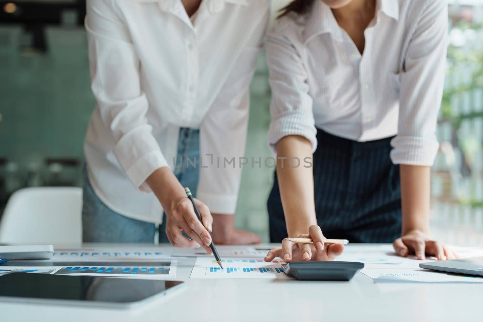 financial, Planning, Marketing and Accounting, Asian woman Economist using calculator to calculate investment documents with partners on profit taking to compete with other companies.