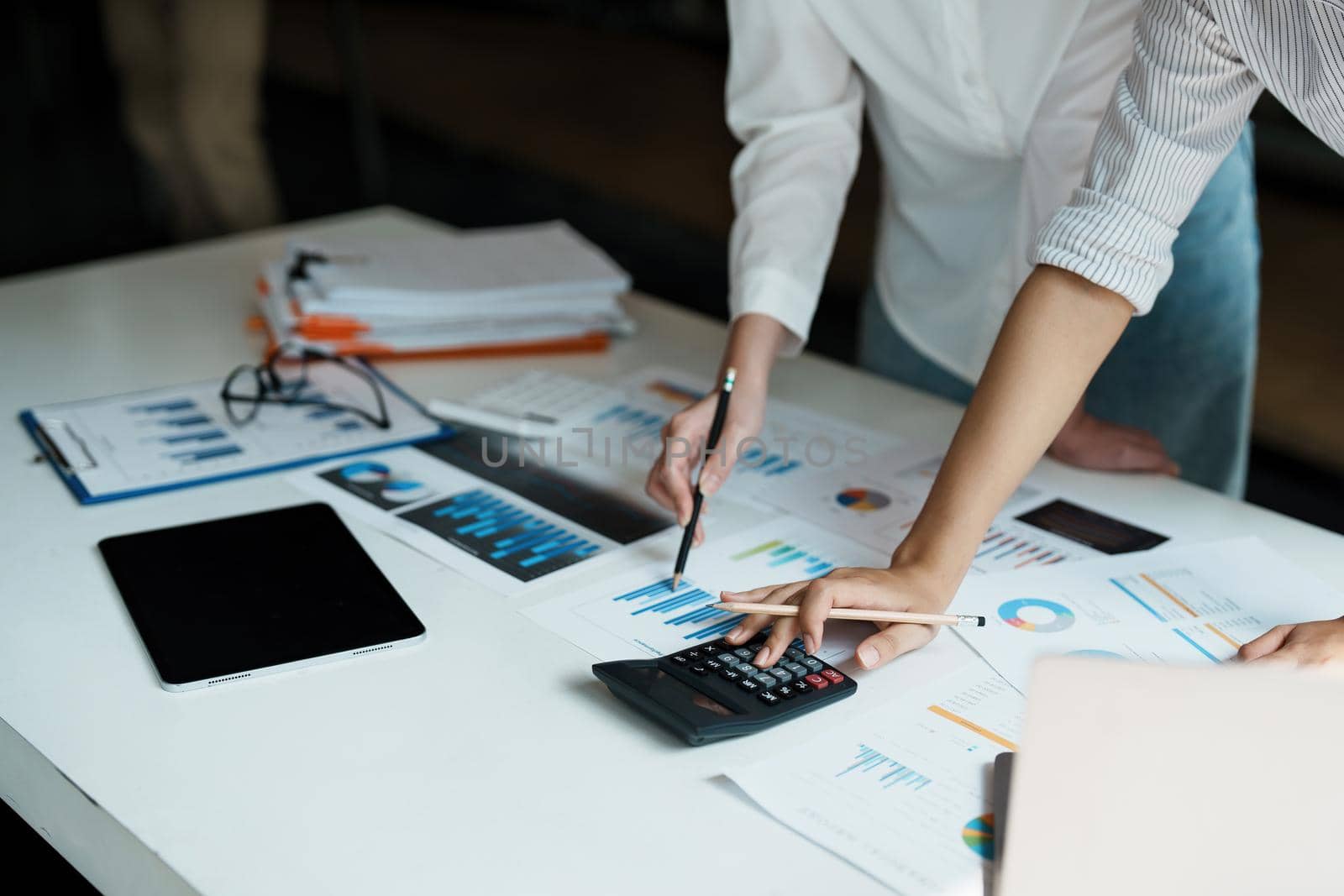 financial, Planning, Marketing and Accounting, Asian woman Economist using calculator to calculate investment documents with partners on profit taking to compete with other companies.