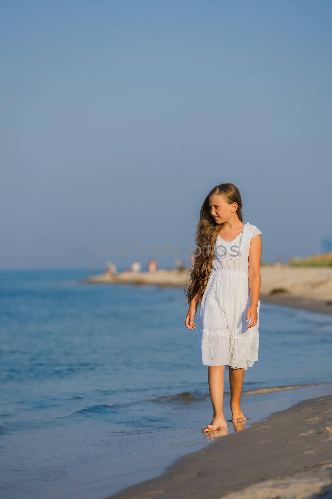 girl in white dress walking on the beach