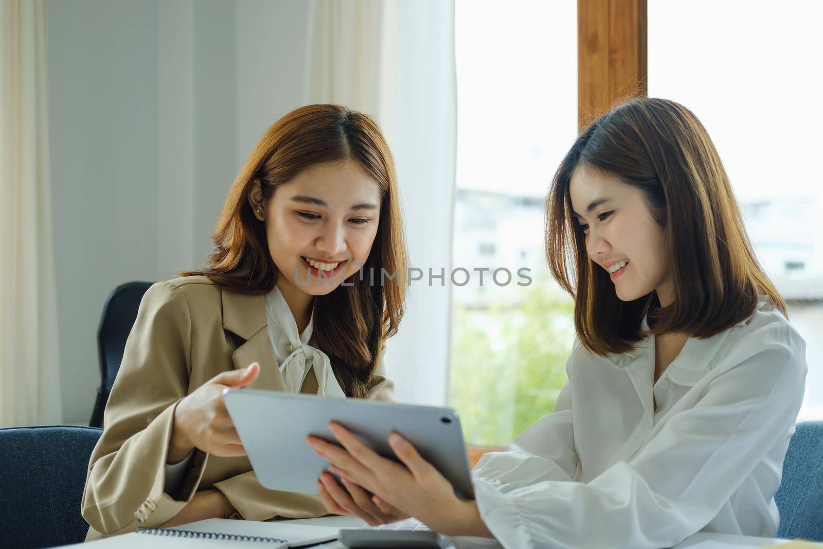 Negotiation, Analysis, Discussion, Portrait of an Asian women economist and marketer using tablet computer to plan investments and financial to prevent risks and losses for the company by Manastrong