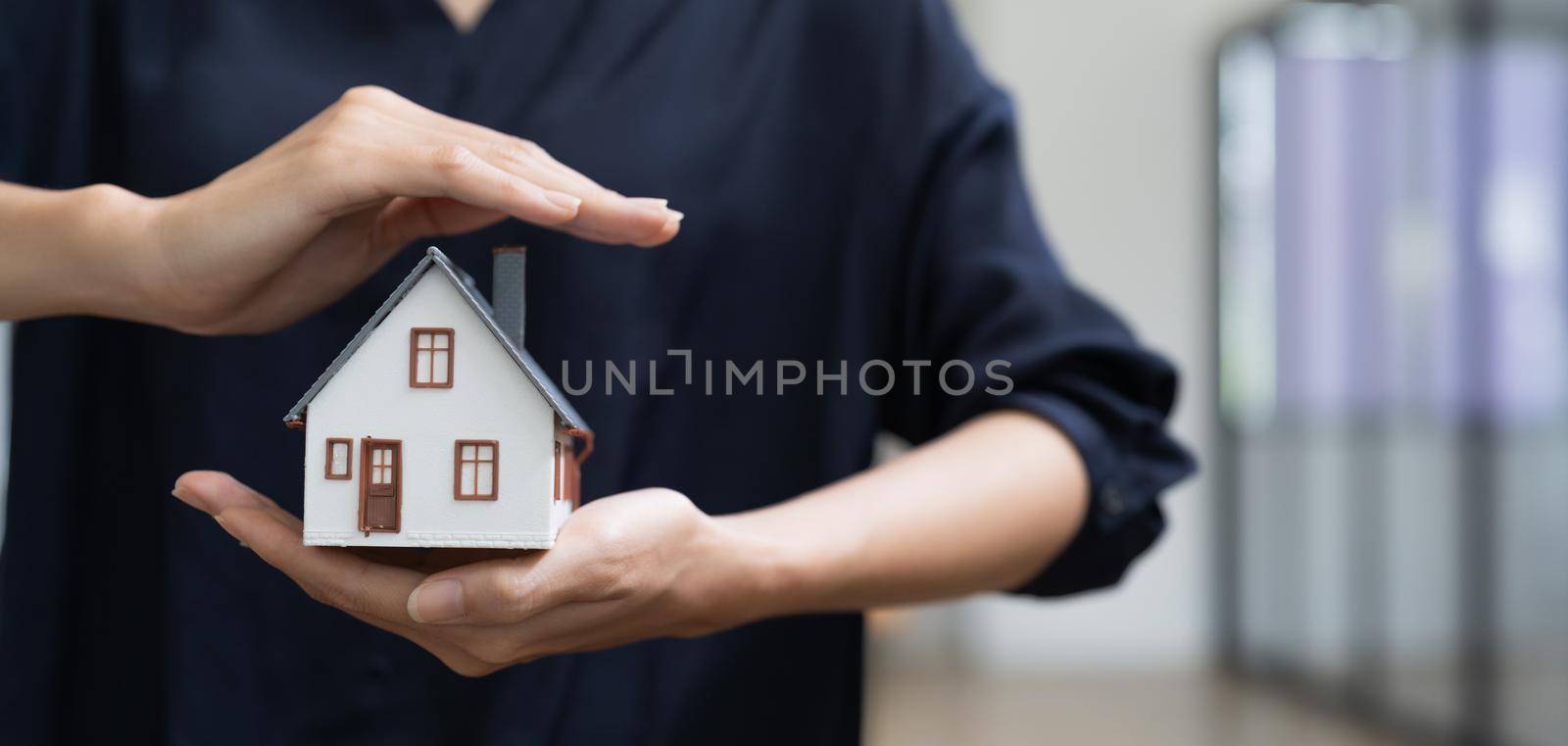 Real estate concept, business woman holding a house icon. House on Hand.Property insurance and security concept. Protecting gesture of female and symbol of house. by nateemee