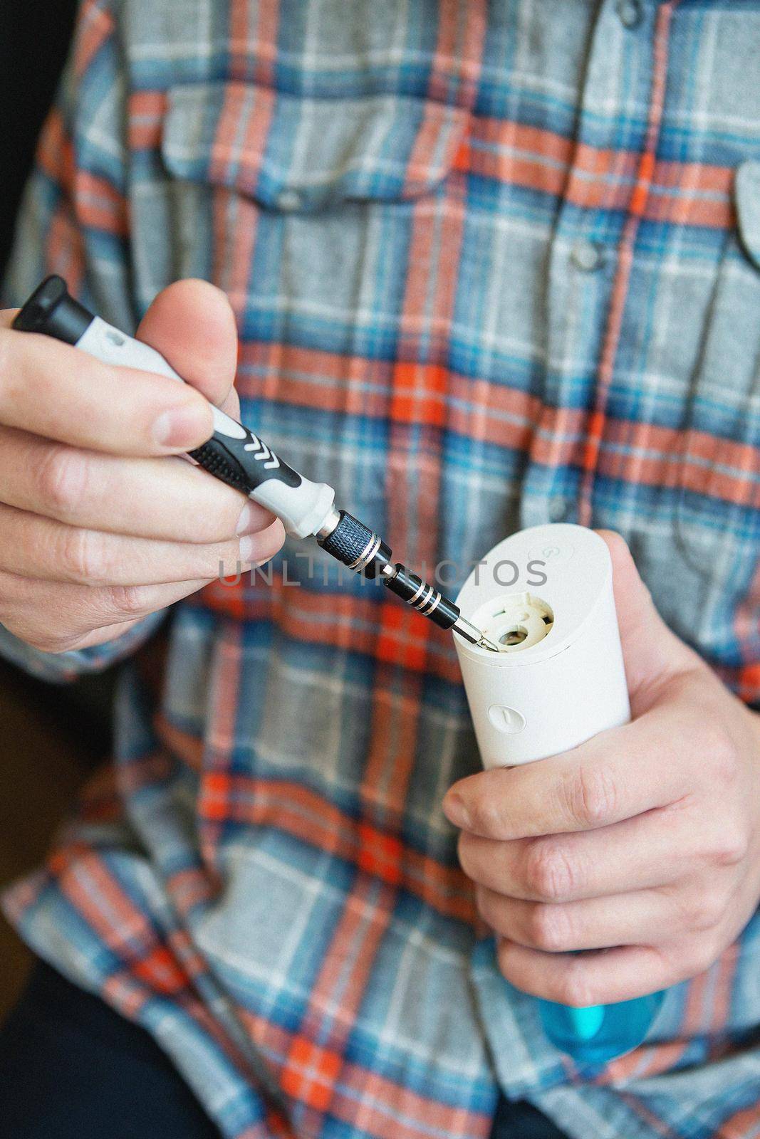 A man in a checkered shirt repairs an irrigator for cleaning teeth. Caries protection. Oral hygiene. by sfinks