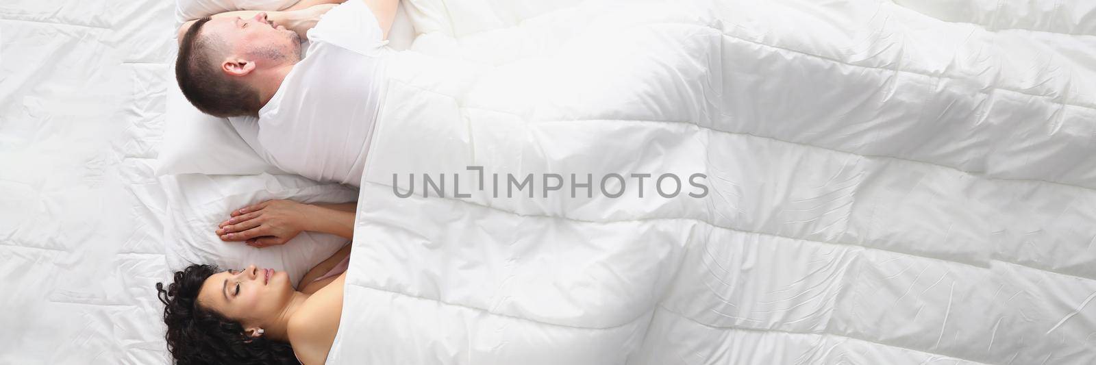 Top view of wife and husband peacefully sleeping on bed, white bedclothes. Wake up and start new day, good morning, every day routine. Good night, comfort, relaxation, family concept