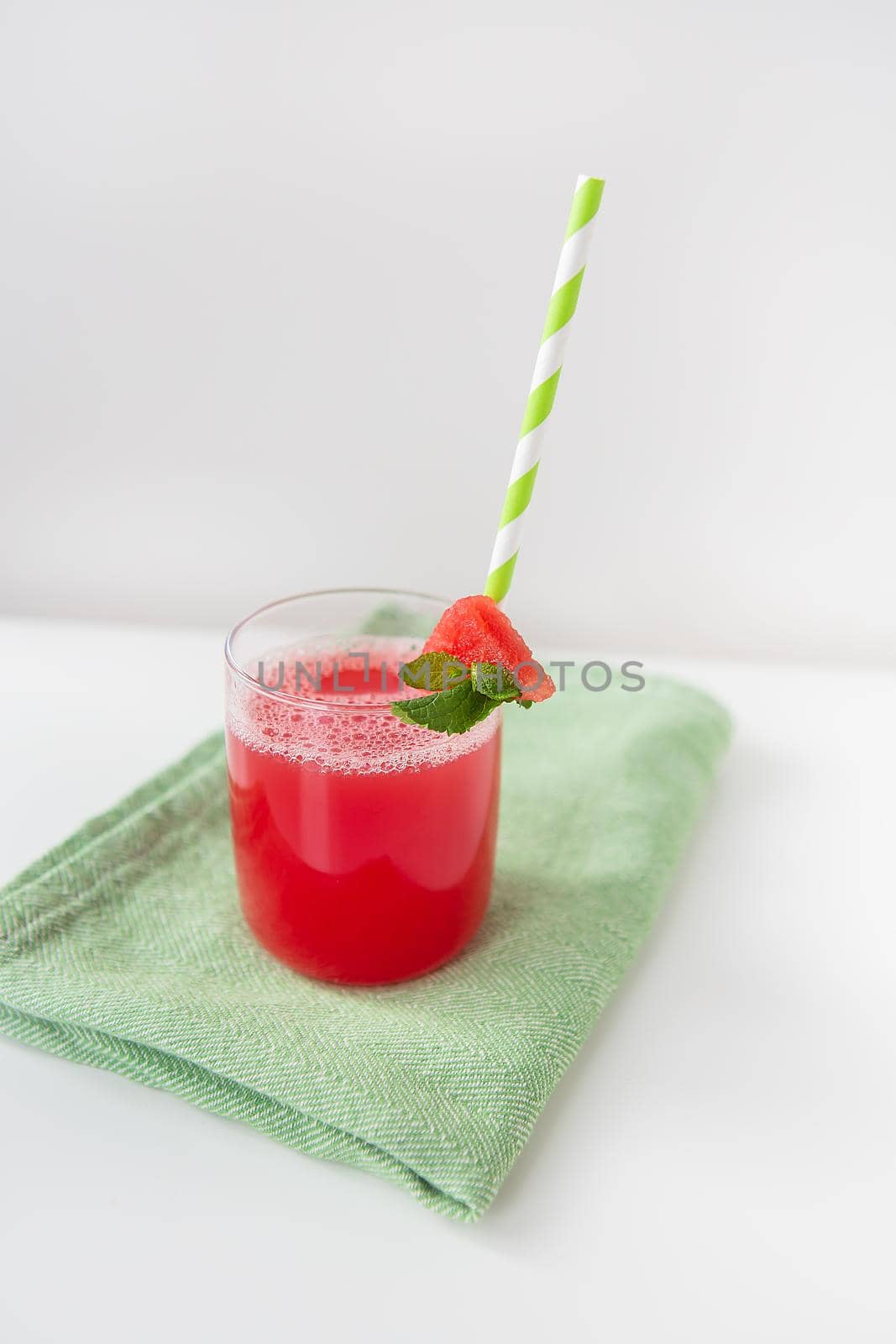 A glass of freshly squeezed fresh watermelon juice, a healthy watermelon and mint leaf smoothie is on a green napkin