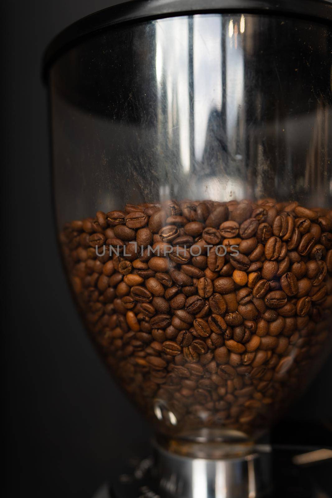 Coffee beans roasted and poured into a coffee grinder. The process of making coffee by a barista. Close-up