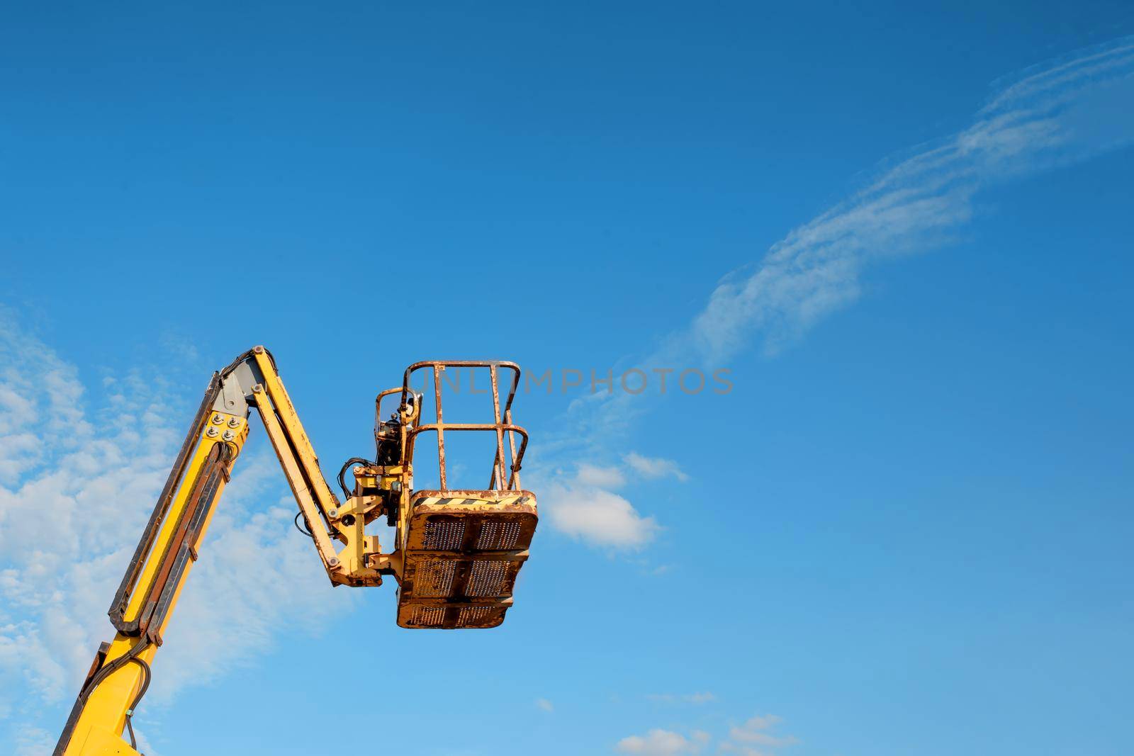 Telescopic boom lift rised up on blue sky background delivered to constraction site ready to be used by steel frame erectors, roofers and painters by Iryna_Melnyk