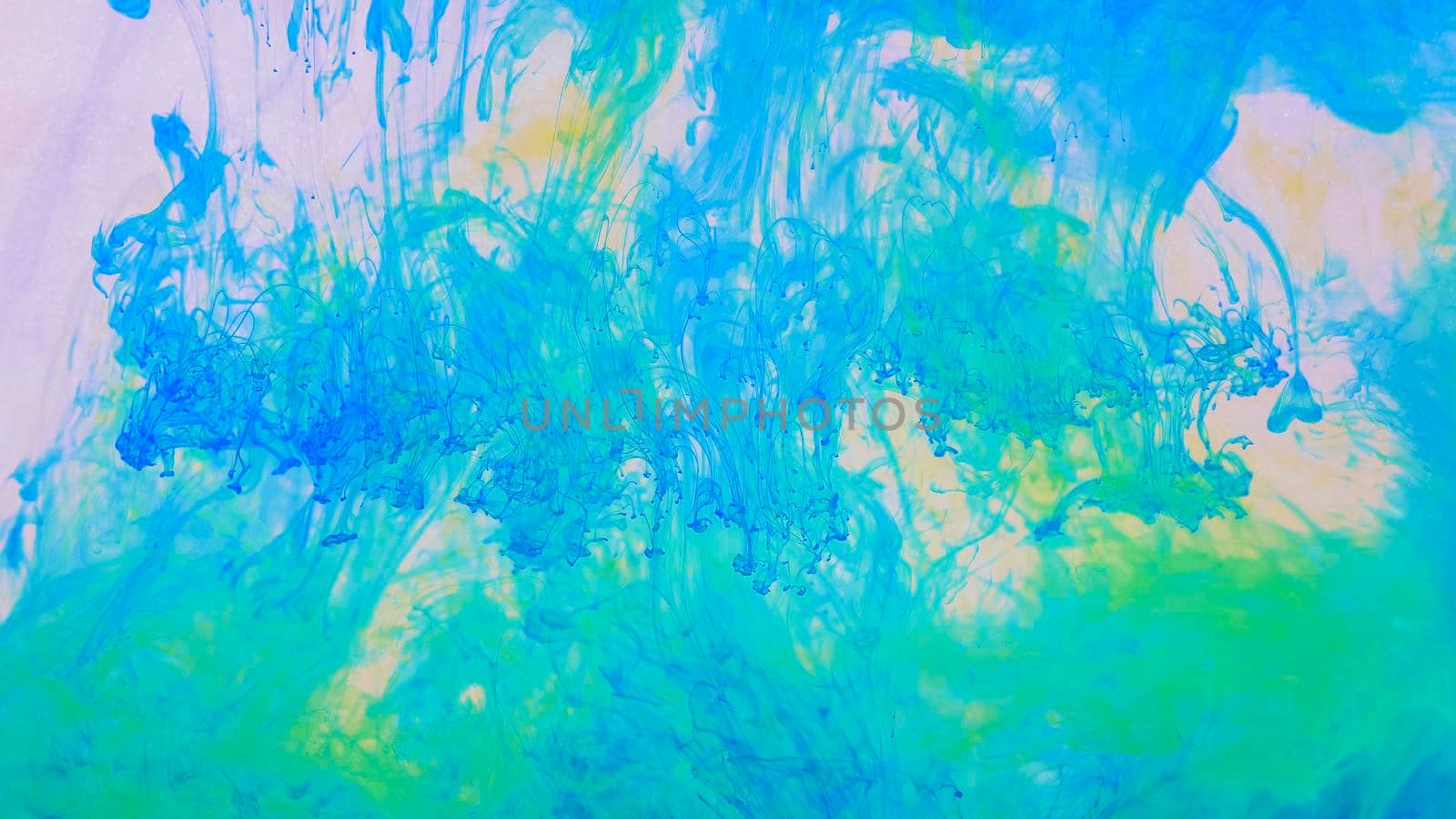 Drops of blue and yellow paint dissolved in water. Shades of green. Deep ink spaces. Unique, natural background.