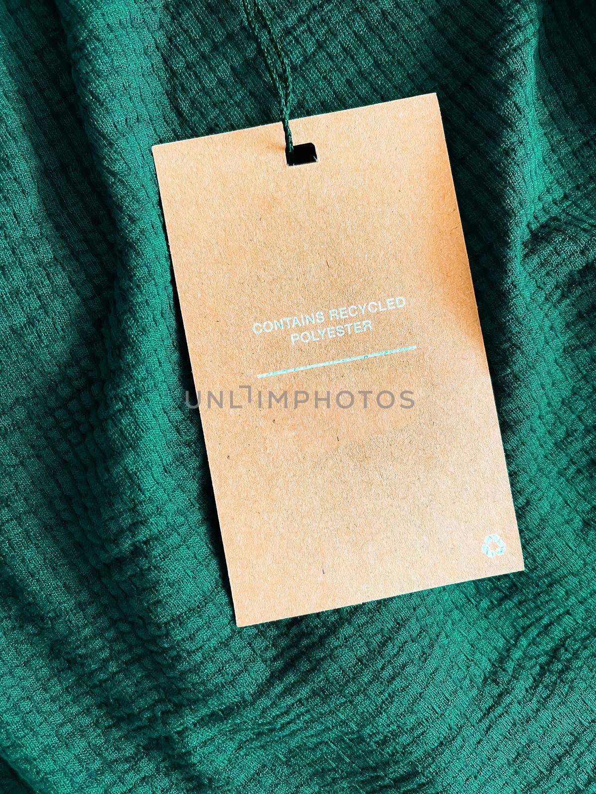 Contains recycled polyester fashion label tag, sale price card on luxury emerald green fabric background, shopping and retail concept