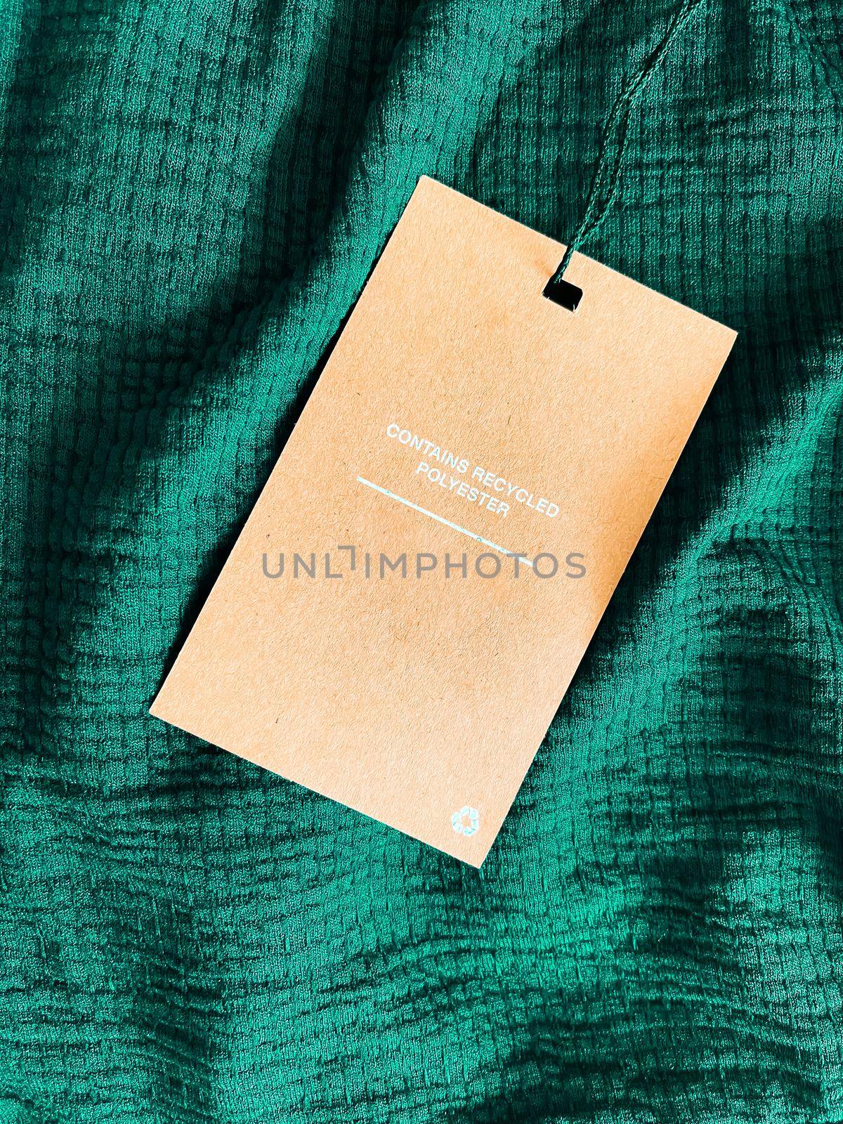 Contains recycled polyester fashion label tag, sale price card on luxury emerald green fabric background, shopping and retail by Anneleven