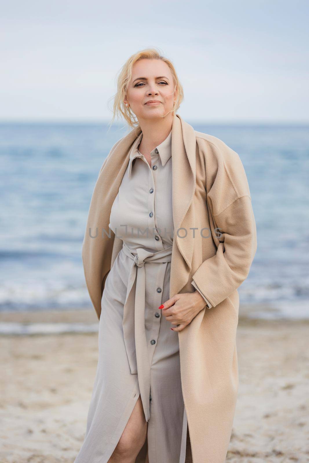 woman aged walking on the beach against the background of the sea