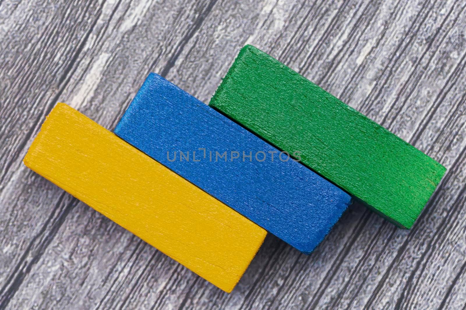 Three colorful wooden cubes against wooden background. Flat lay. Copy Space. by JennMiranda