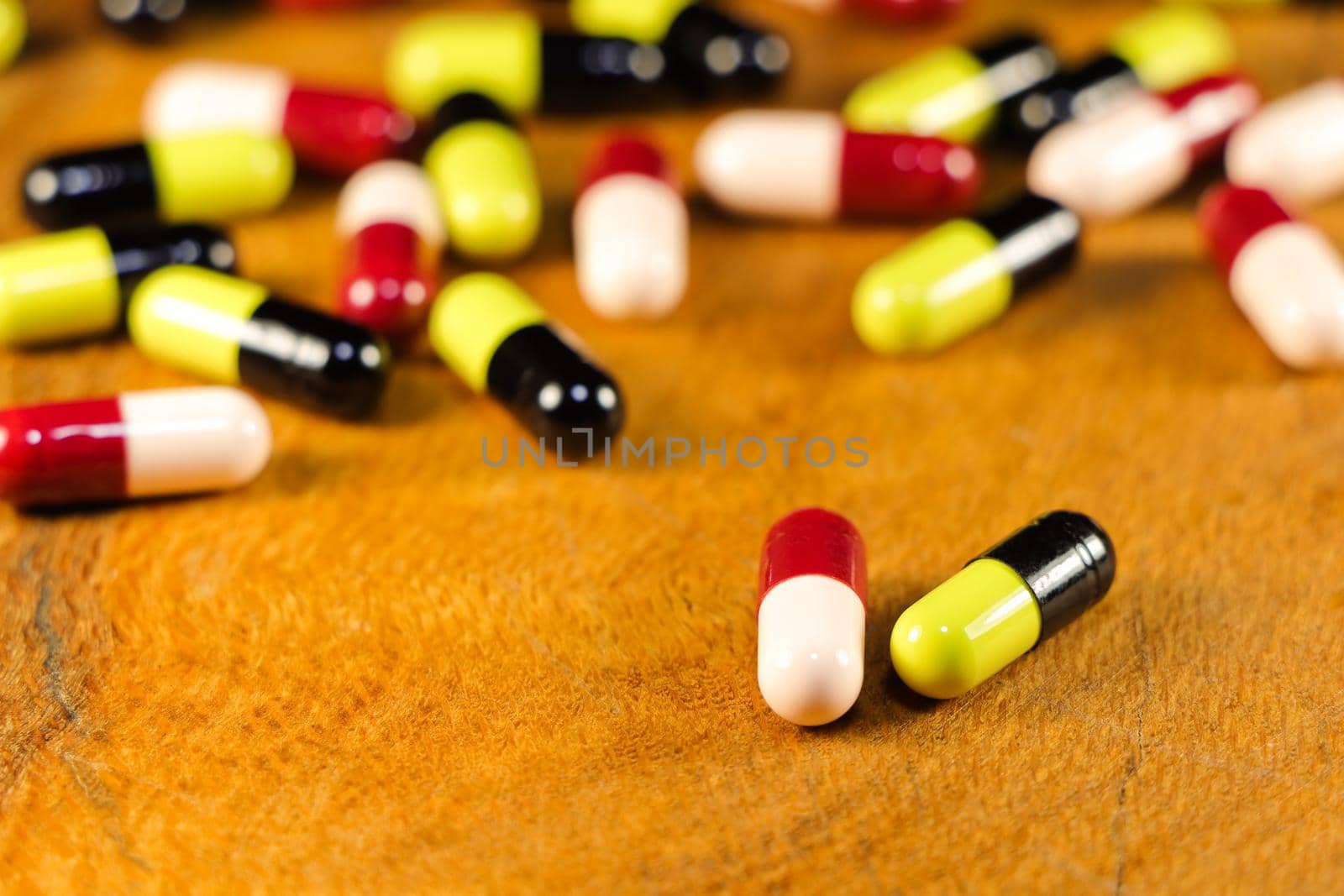 Medical prescription drug capsules on natural wooden surface abstract close-up