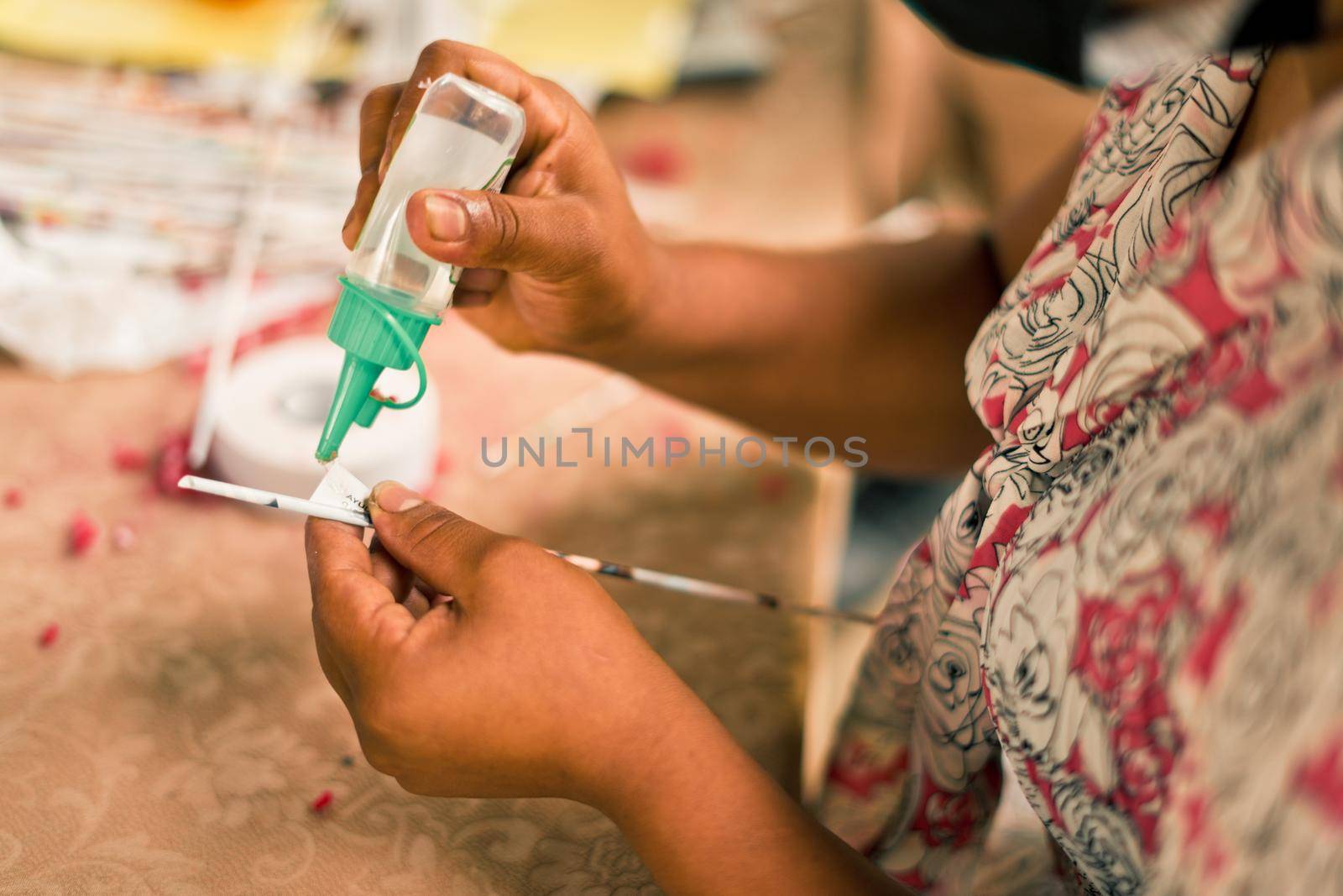 Unrecognizable Nicaraguan woman putting glue on paper to make crafts and recycle waste