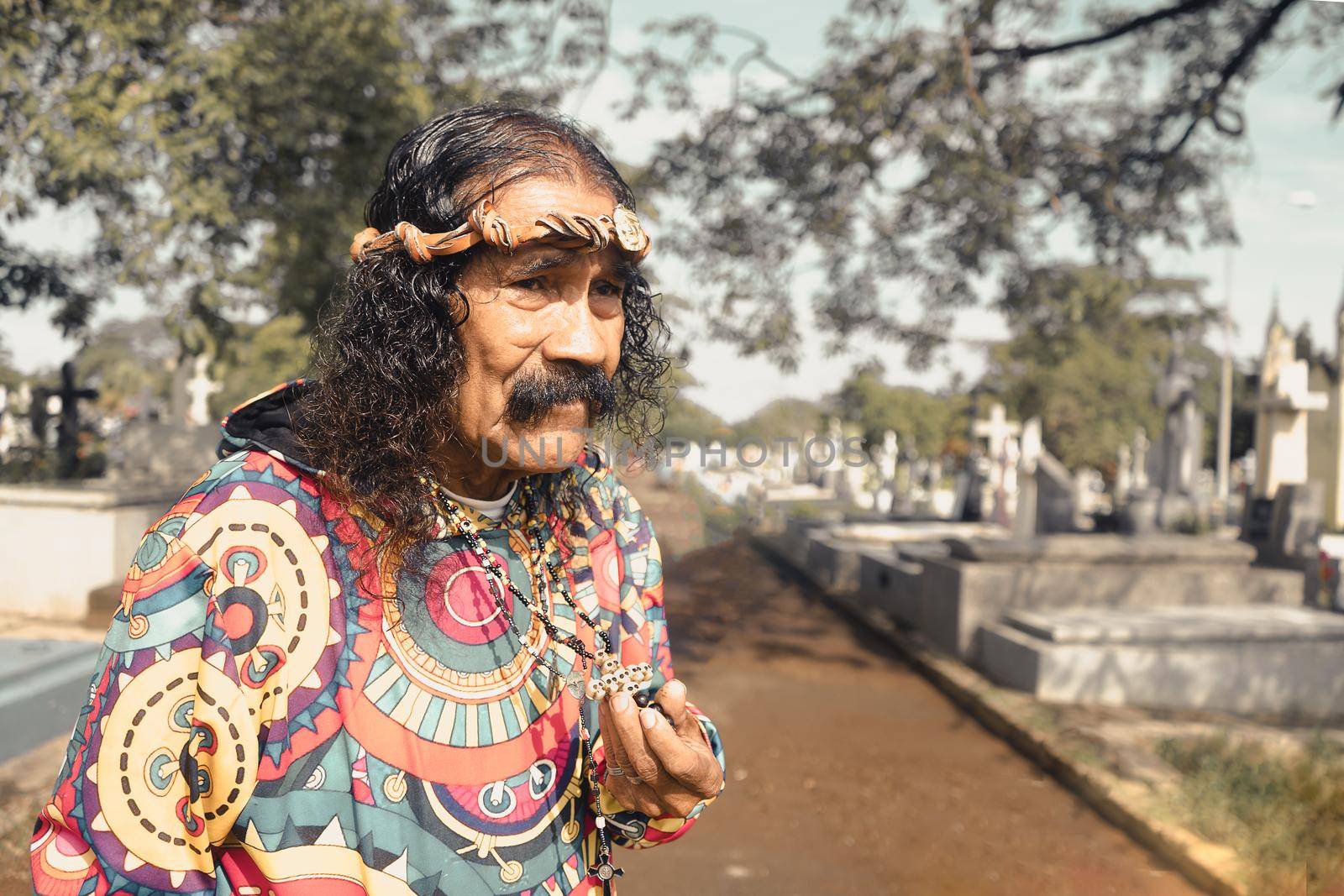 Devotee of Santa Muerte playing her skull and crossbones crucifix in a cemetery in Managua Nicaragua