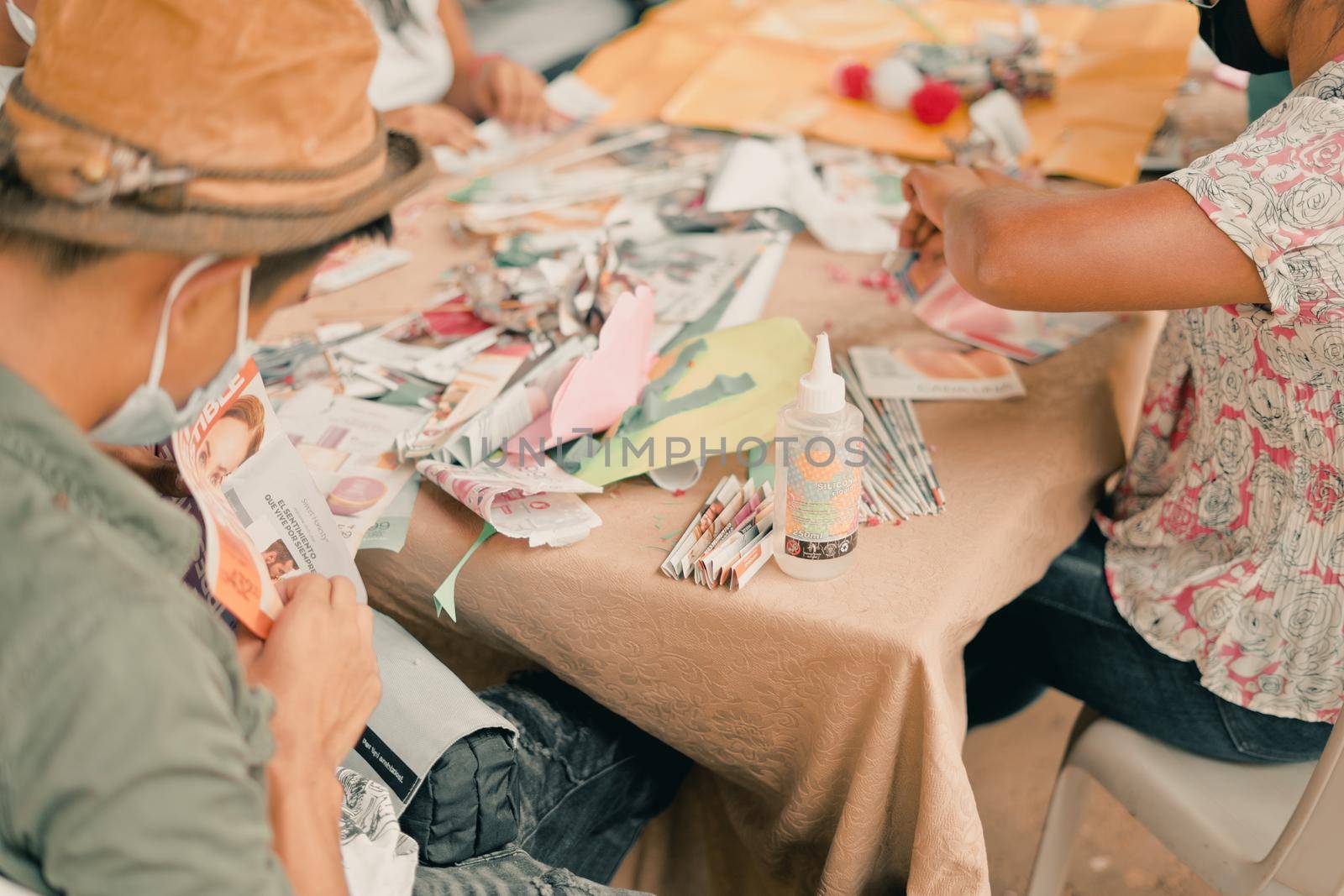 Unrecognizable mother and son from Nicaragua recycling paper from magazines to make crafts