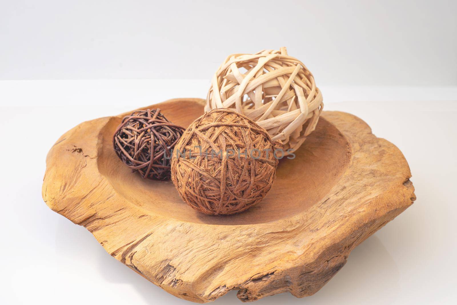 wicker balls from a vine of different natural colors on a wooden tray on a light background