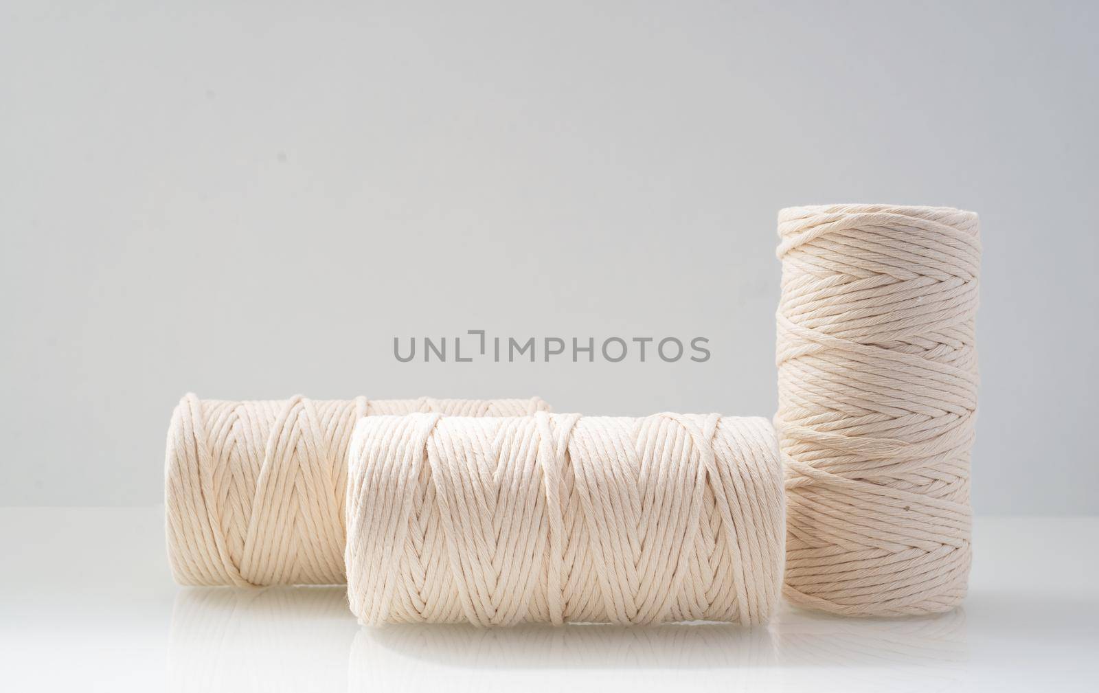 macrame threads wound bobbins of natural beige color are located on a light background