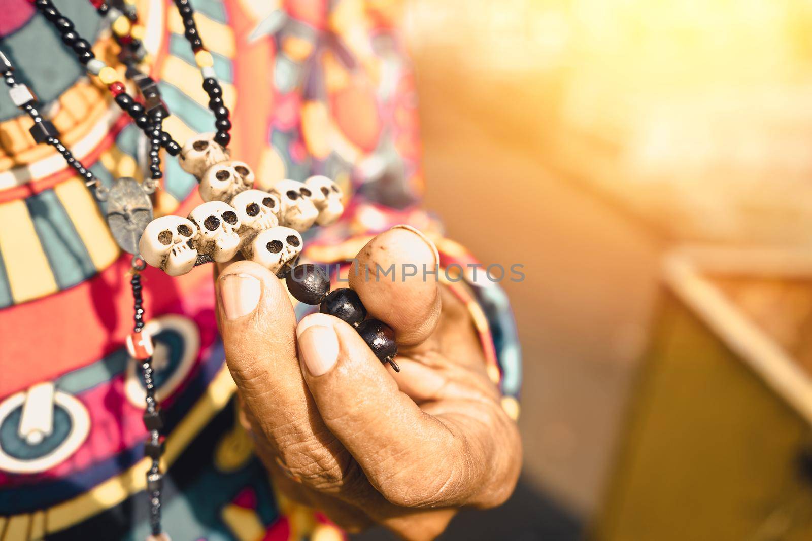 Closeup to the hand of a devotee of santa muerte holding his crucifix of skulls in a cemetery in managua nicaragua