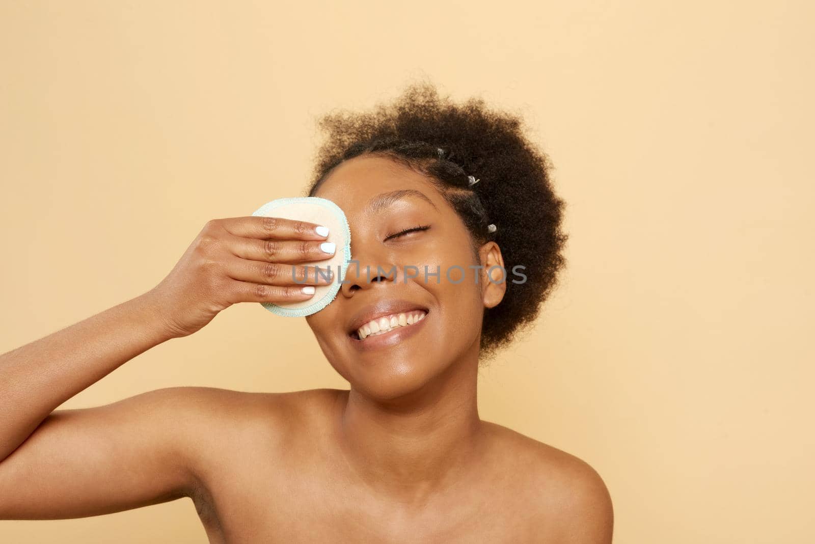 Beautiful young black woman with removal disk on beige background. Eco-friendly