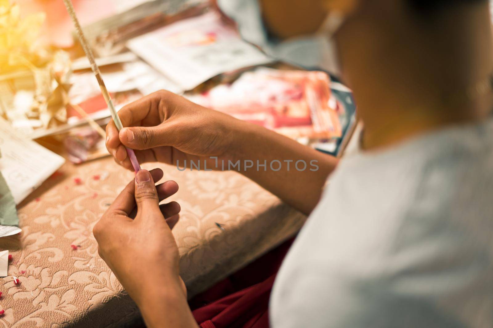 Unrecognizable young Nicaraguan woman making crafts with recycled magazine paper