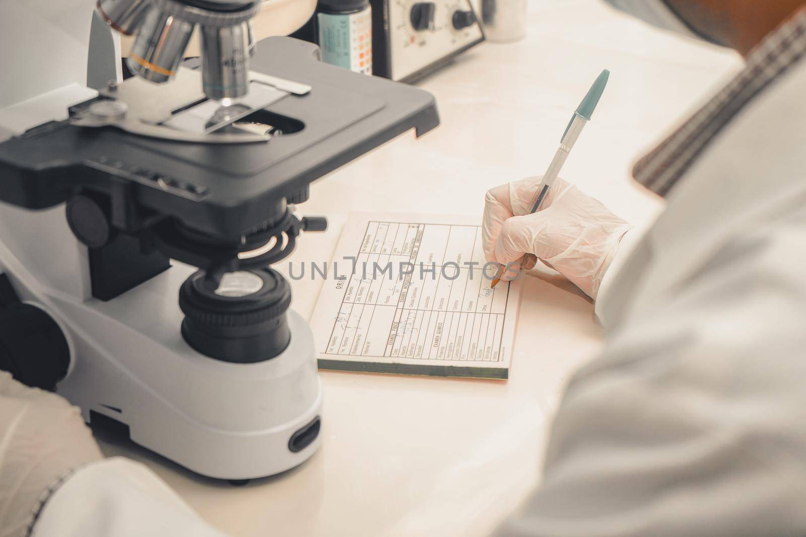 Latin Clinical analyst from Nicaragua writing down the results of a laboratory sample examined under a microscope