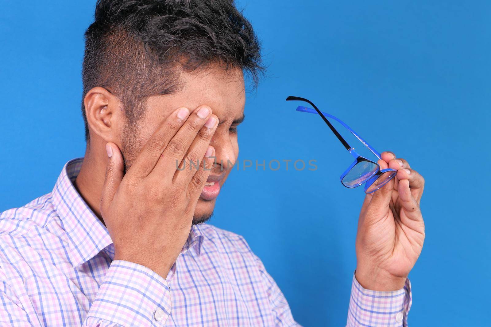 Close up of upset man suffering from strong eye pain.