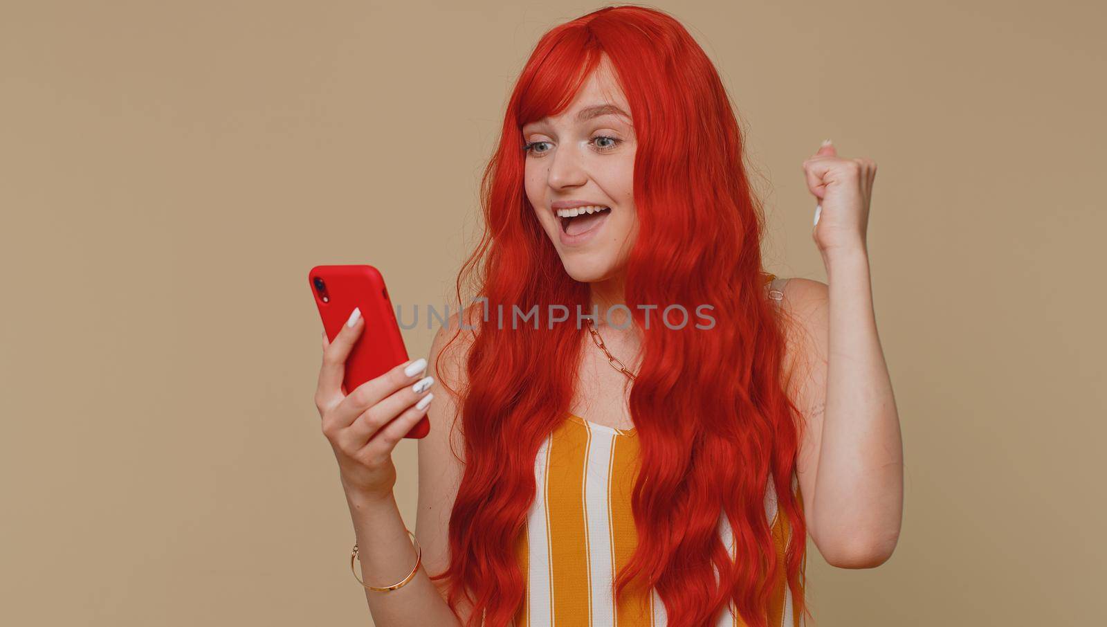 Happy excited joyful woman in striped tank top use mobile cell phone typing browsing shouting say wow yes found out great big win, good news, lottery goal achievemen, celebrating success, winning