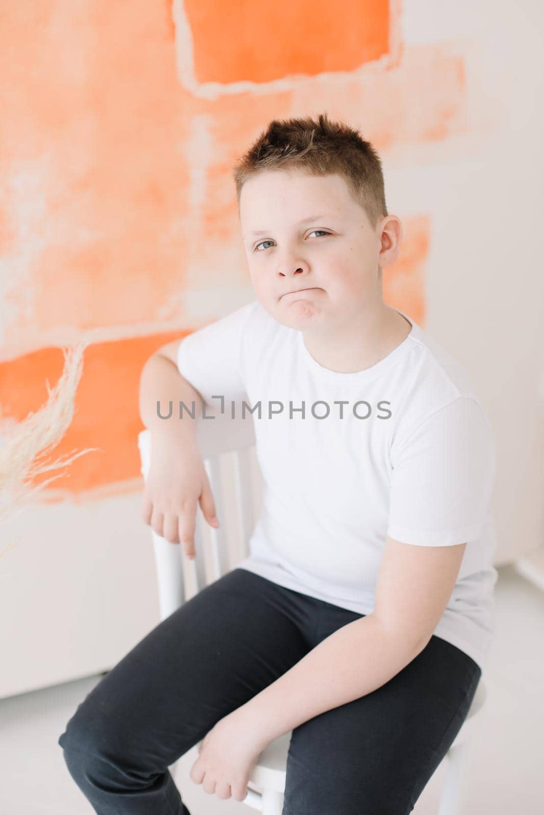 Close up portrait of a happy cute boy in a white t-shirt looking at camera on a colorful background. Childhood, style, school concept.