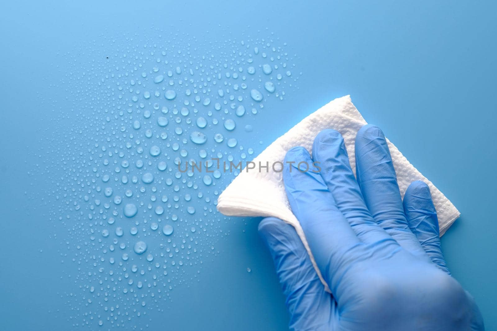 hand in blue rubber gloves cleaning table with towel .