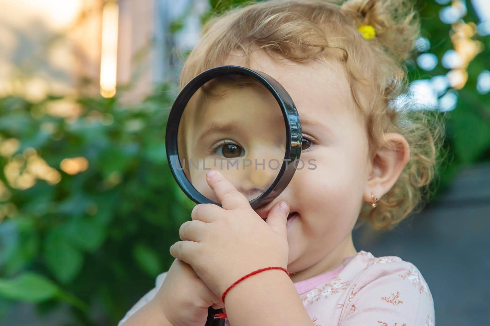 A child with a magnifying glass is studying the world. Selective focus. by yanadjana