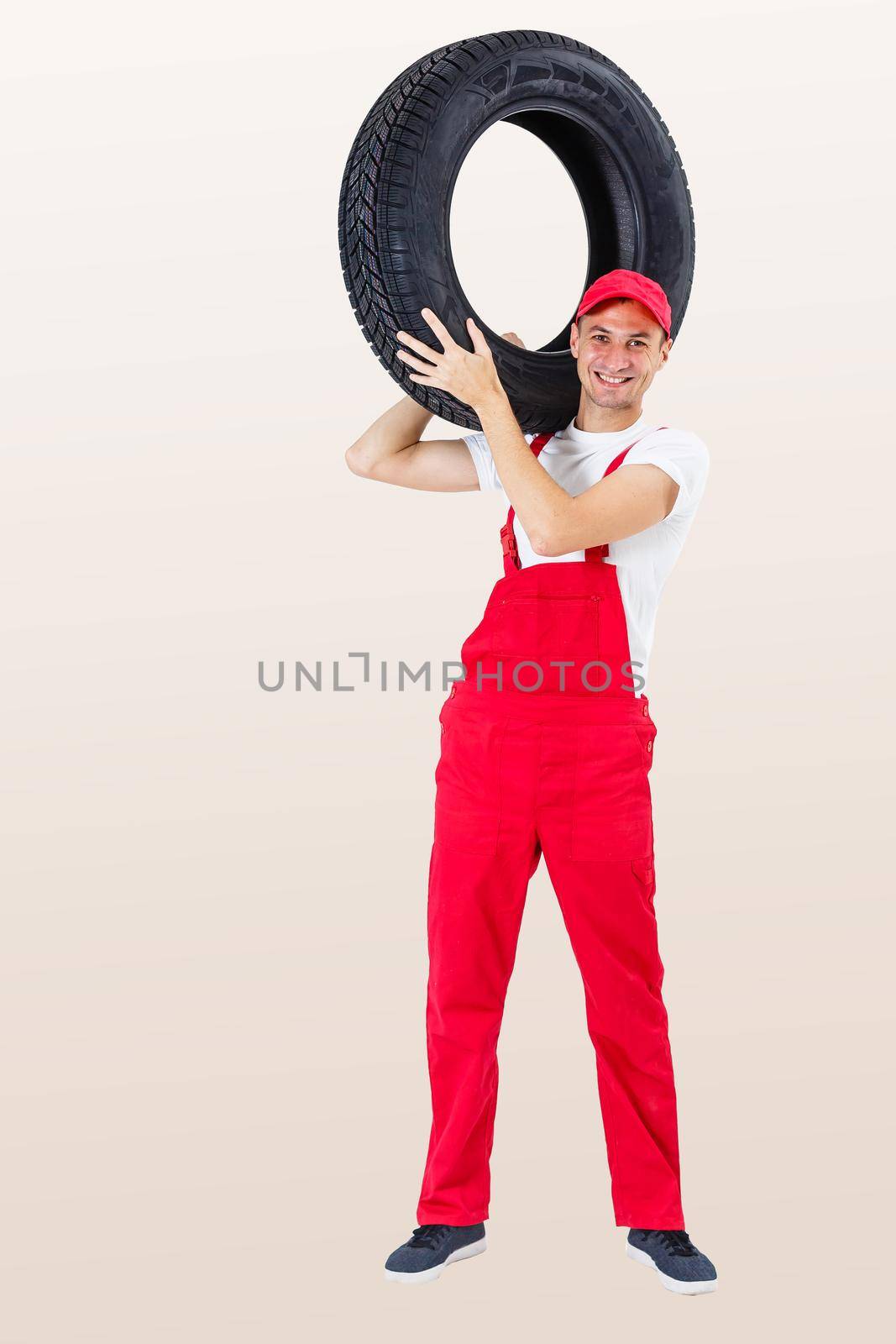 working man in full growth holds a tire on a white background