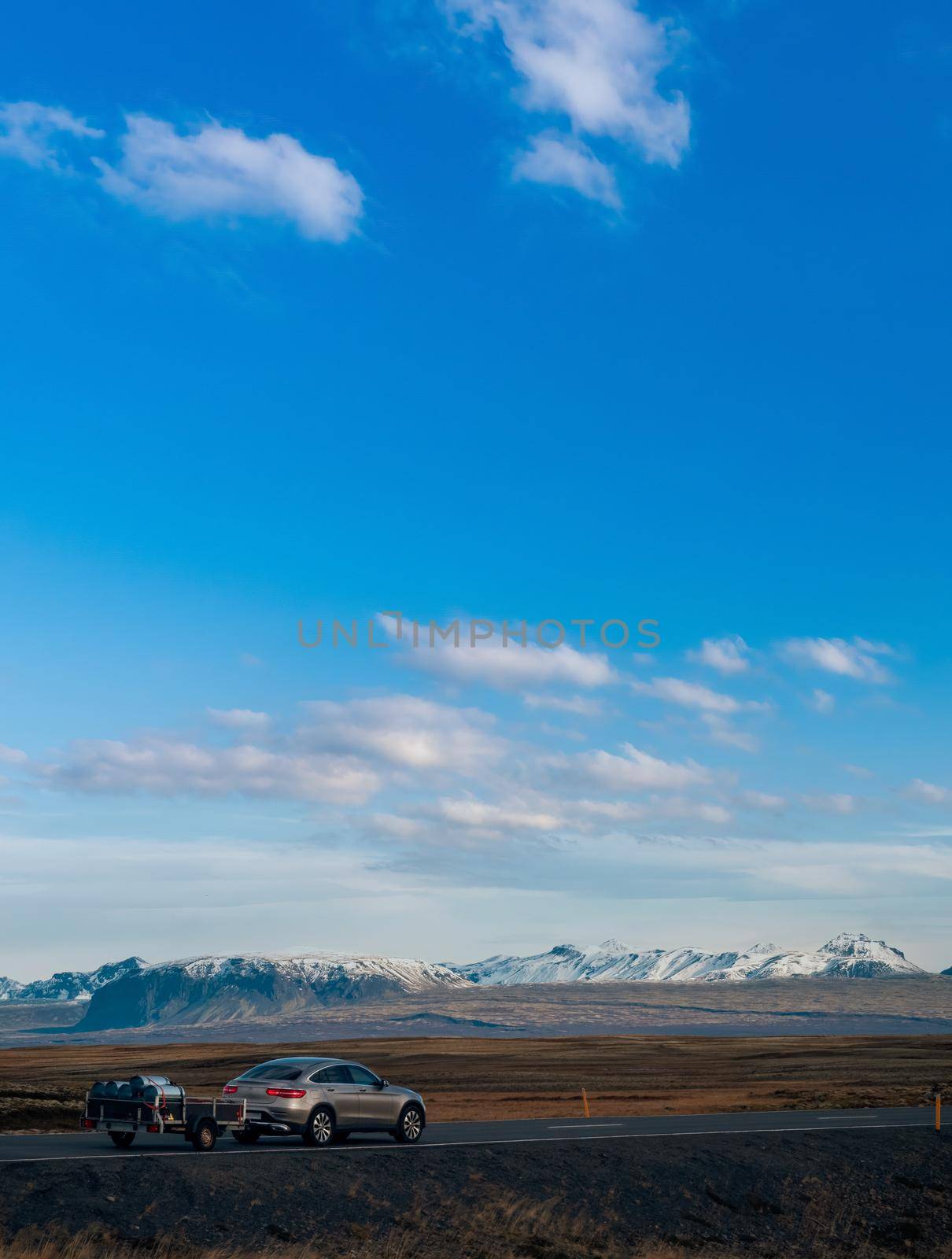 Car with trailer over the straight Iceland road under blue sky