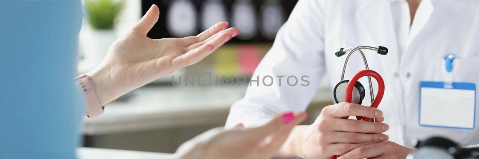 Close-up of therapist hands holding stethoscope. Woman at doctor appointment. Physician communicating with patient in clinic office. Healthcare and medicine concept