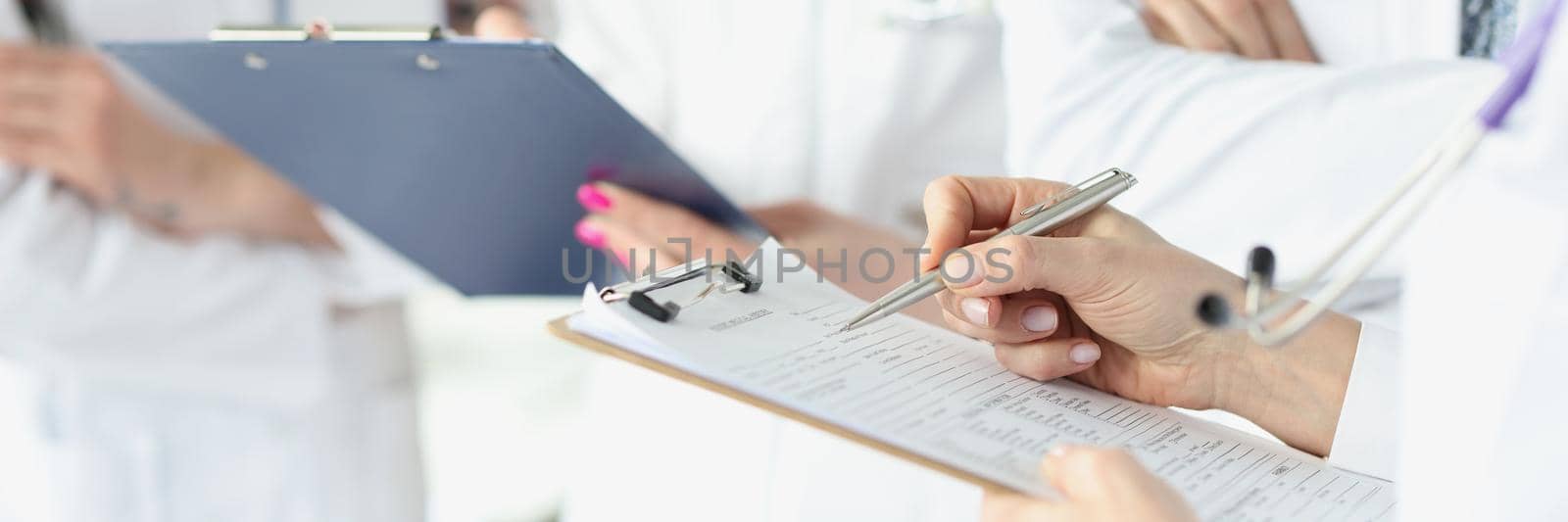 Close-up of therapist hands holding clipboard and filling forms. Physicians making appointment and discussing treatment. Healthcare, teamwork and medicine concept