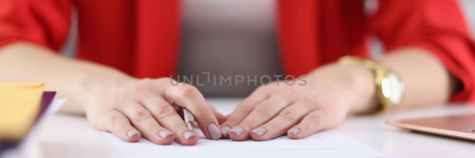 Close-up of woman hands with perfect manicure holding pen. Office manager sitting at workplace. Boss signing documents or profitable contract. Paperwork or good deal idea