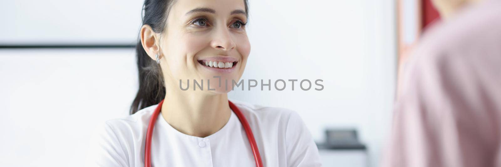 Portrait of smiling gynecologist looking at patient with gladness. Physician pointing on results of ultrasound. Pregnancy, gynecology and antenatal care concept