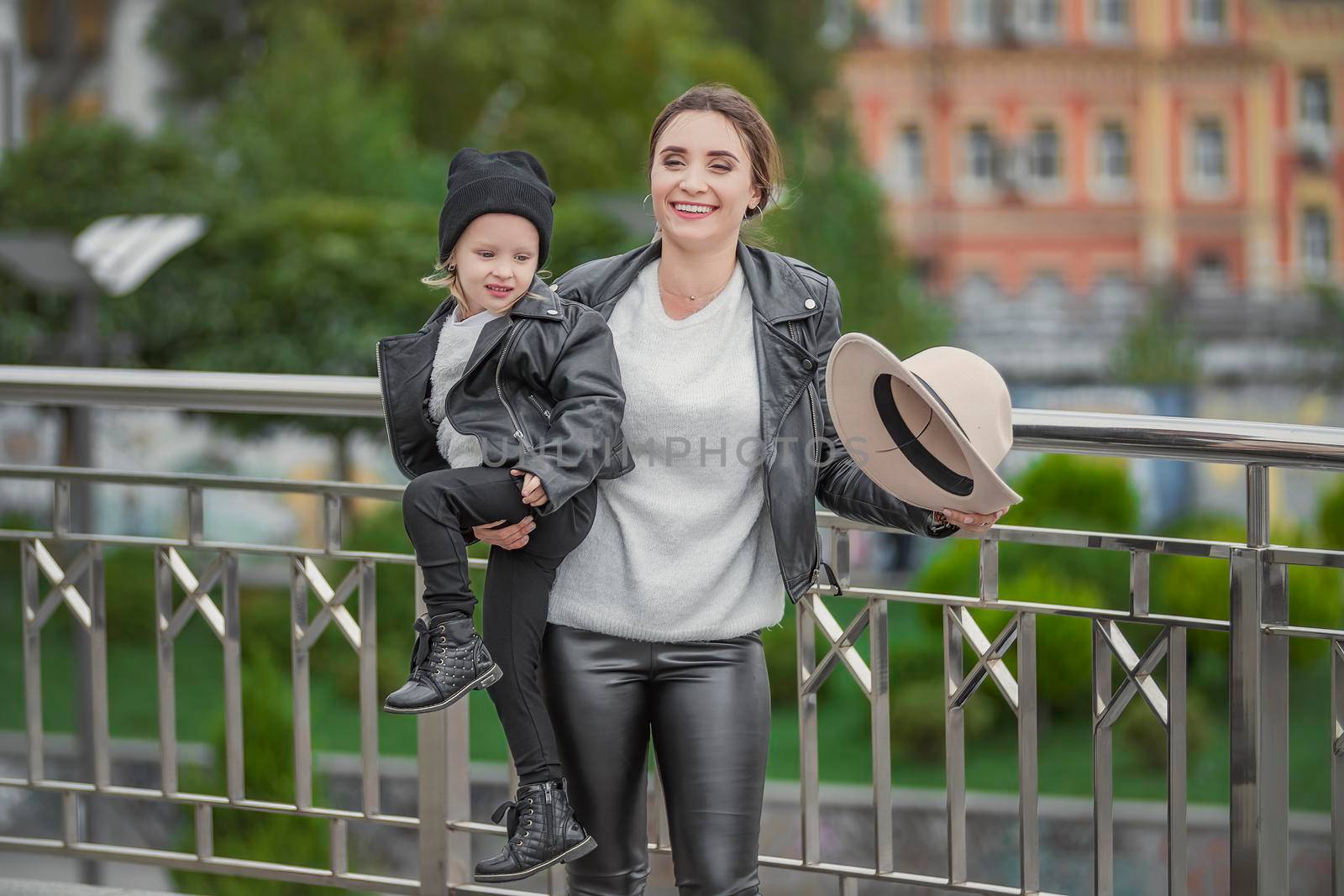 Mom carries her daughter in her arms while walking in the city