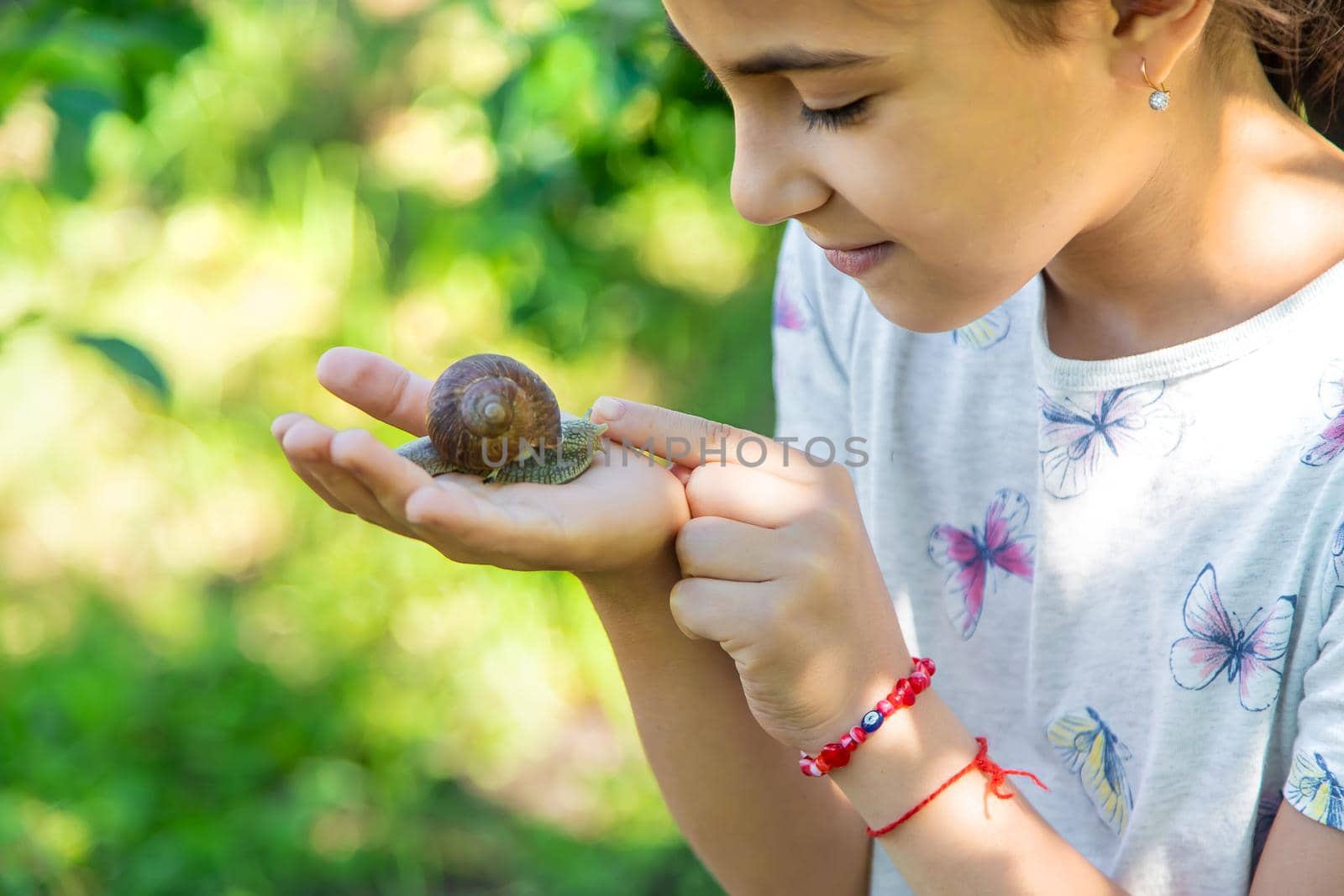 The child examines the snails on the tree. Selective focus. by yanadjana