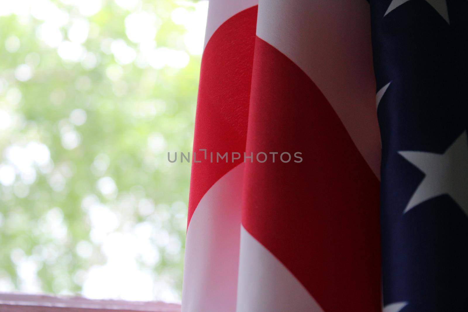 The U.S. flag hangs against a background of green foliage. Flag Day. Memorial Day. Independence Day..