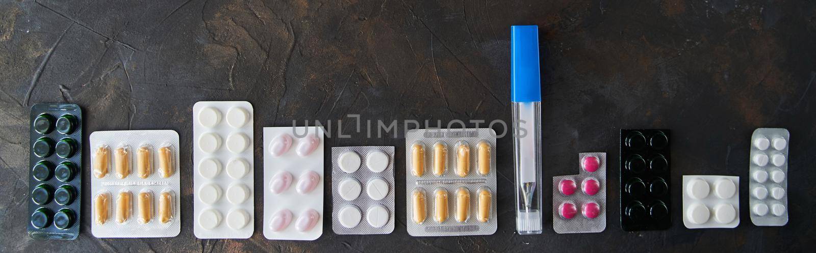 Pills capsules medicine health on dark background, top view by driver-s