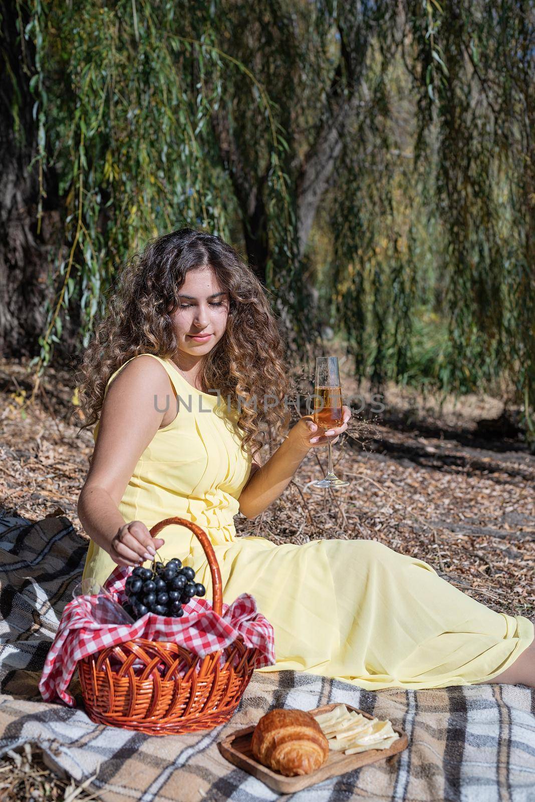 Leisure, free time. Beautiful caucasian woman in yellow dress on a picnic outdoors, sitting next to water