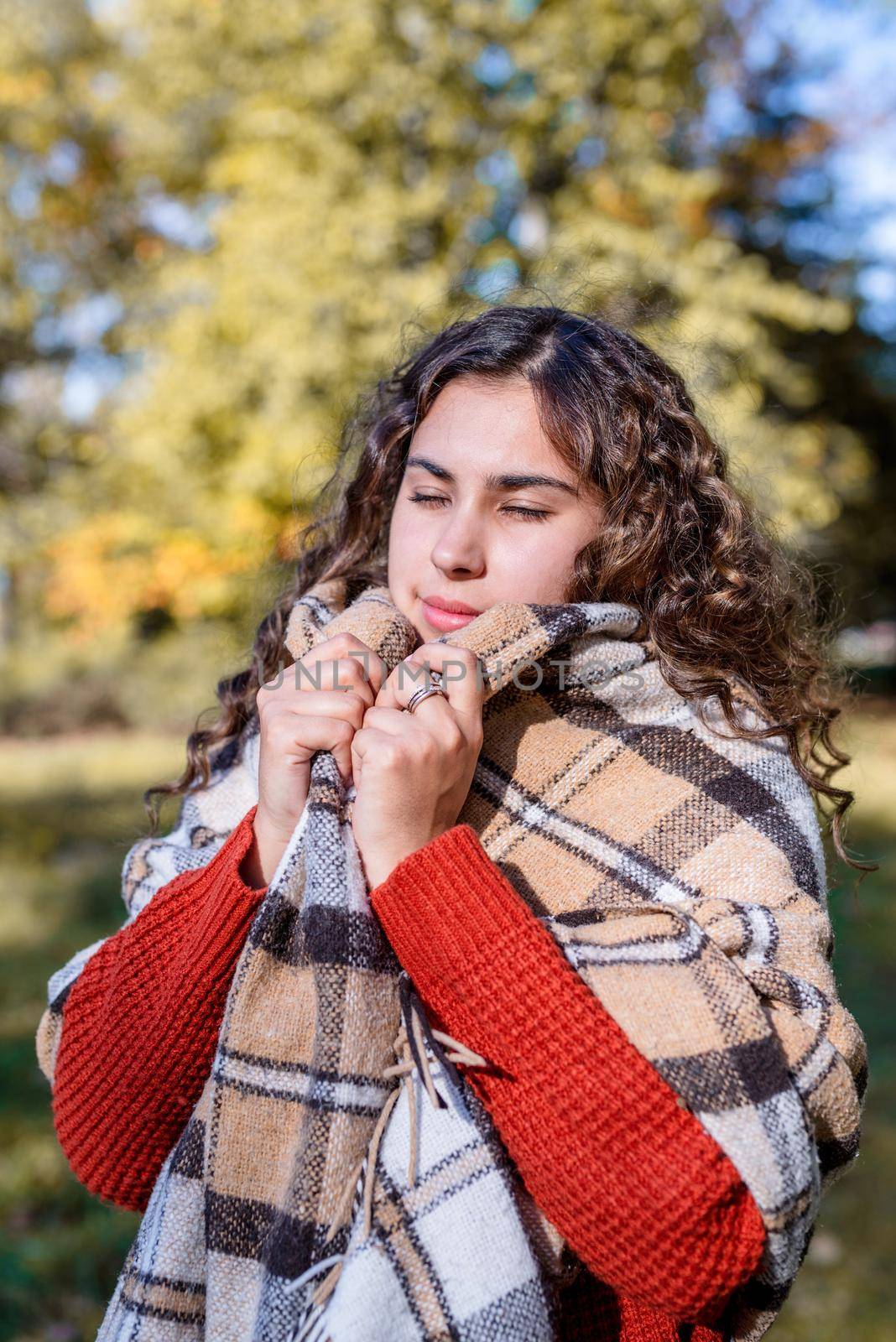 Autumn nature. Portrait of young happy woman in warm plaid in autumn forest