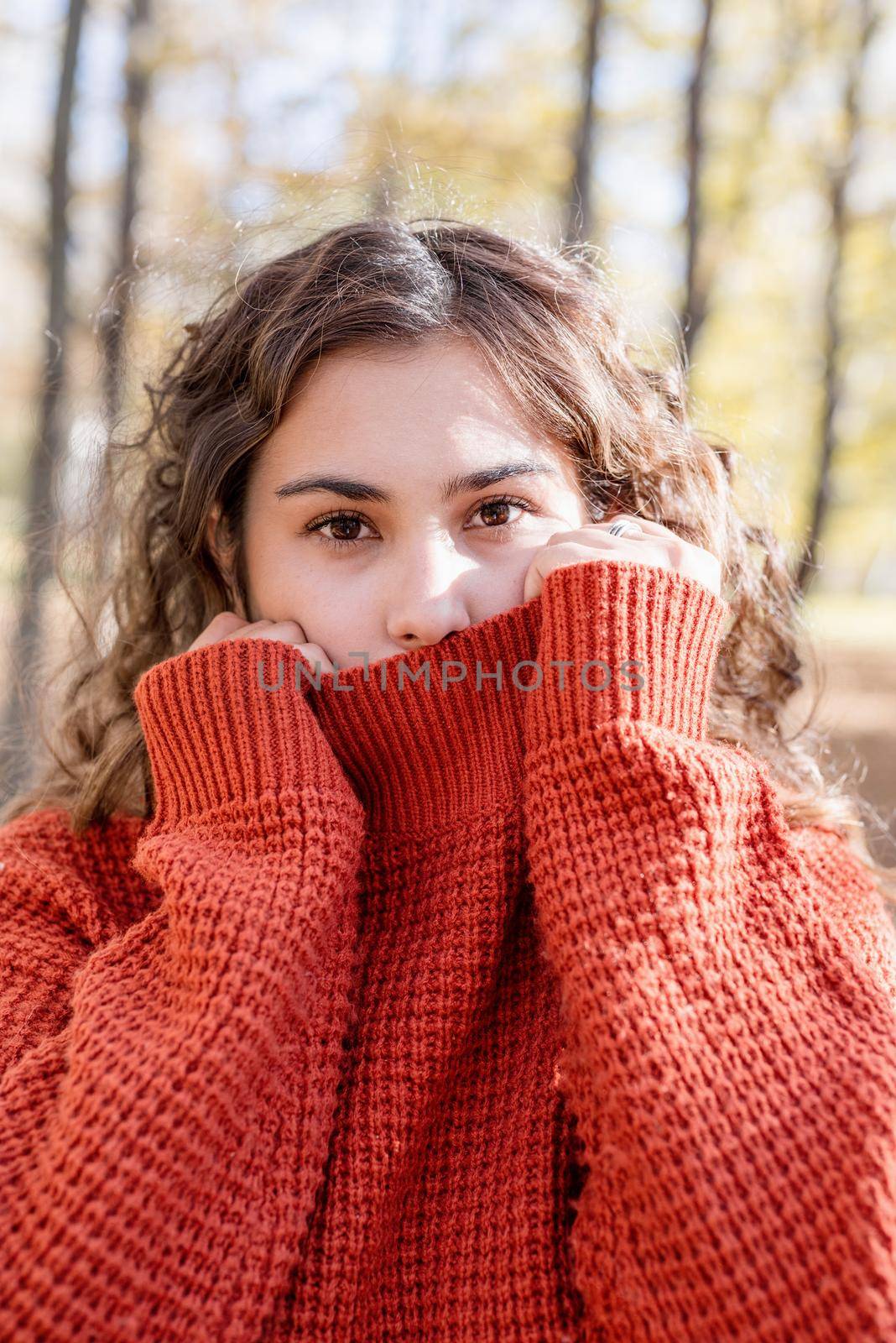 Portrait of young happy woman in warm sweater in autumn forest by Desperada