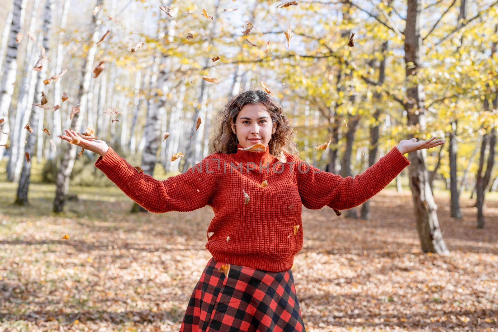 Young happy woman throwing leaves in autumn forest by Desperada