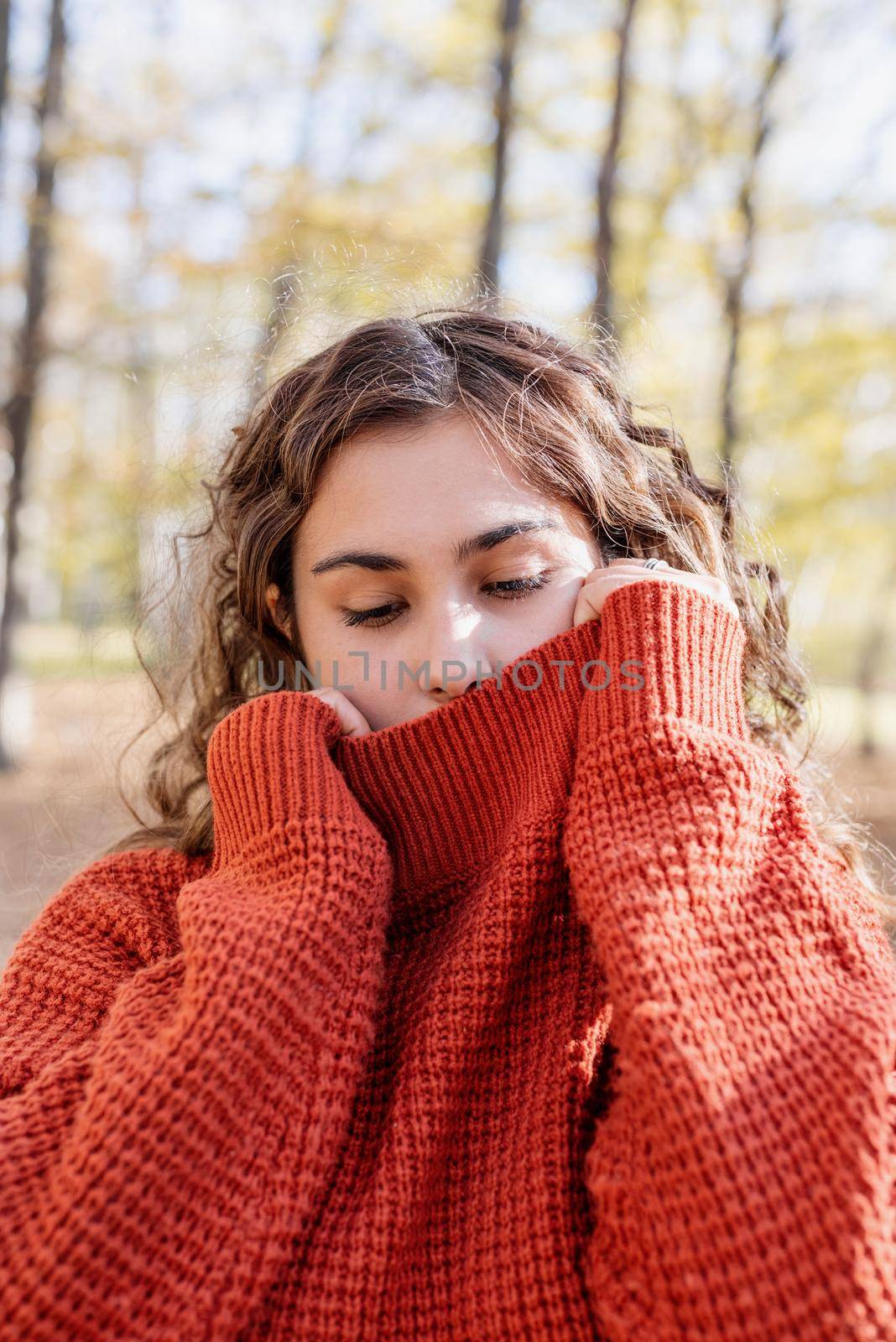 Portrait of young happy woman in warm sweater in autumn forest by Desperada