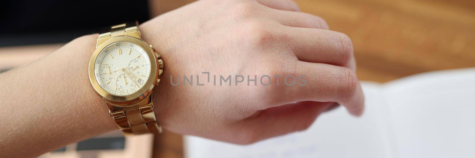 Close-up of woman hand with clock. Businesswoman checking time and writing schedule in notepad. Time management, work organization, punctuality and deadline concept