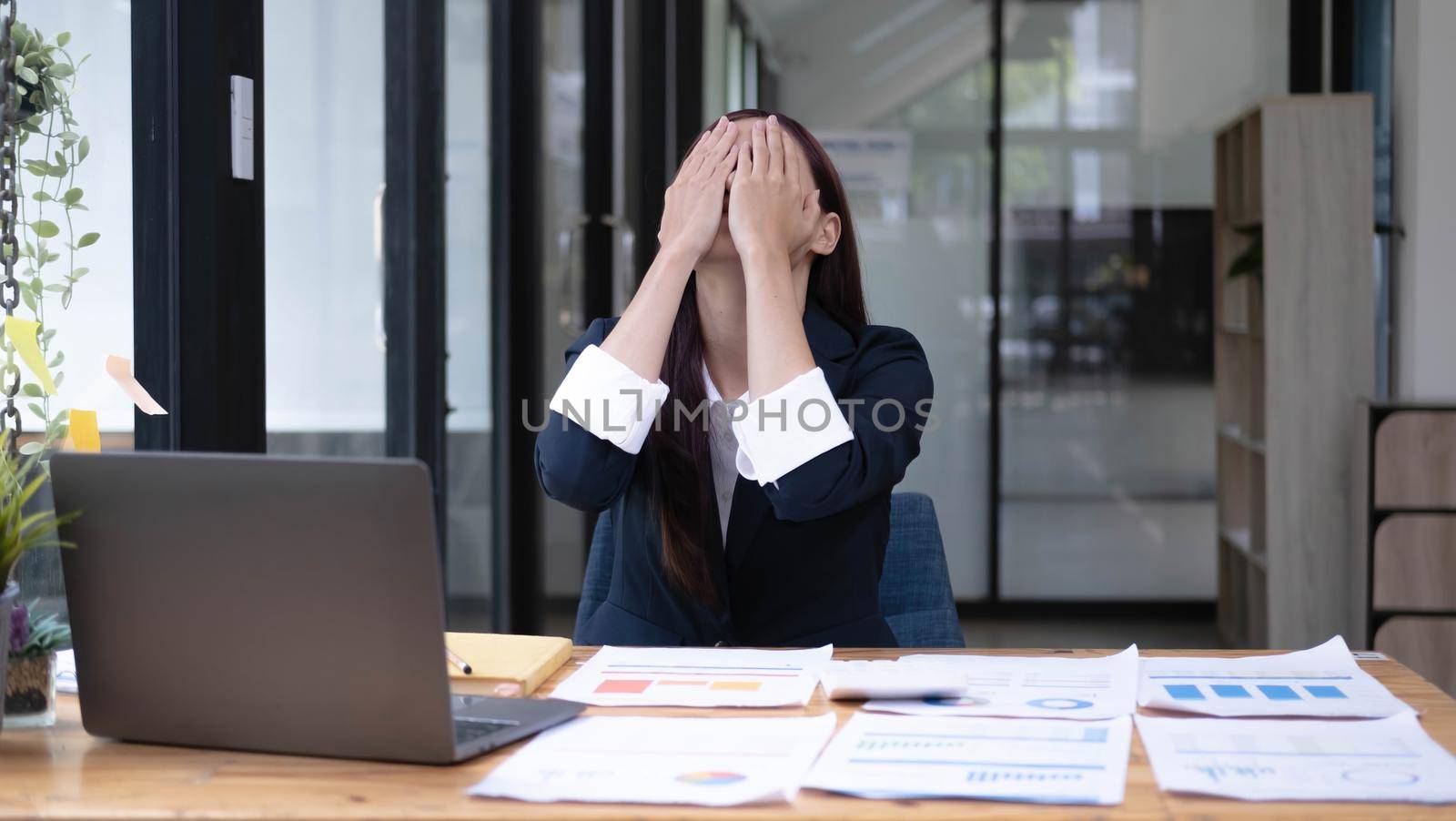 Image of an Asian business woman is stressed, bored, and overthinking from working on a tablet at the office..